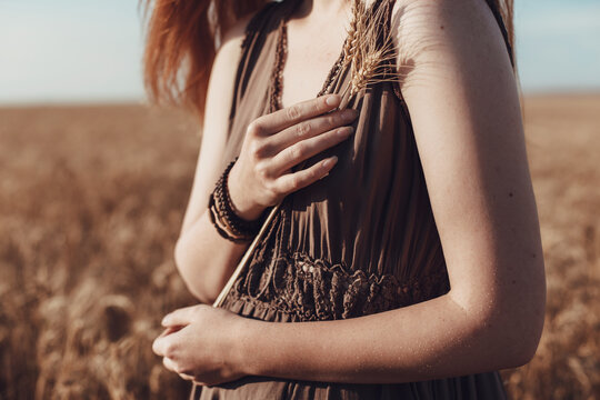 Young ginger woman in the wheat field looking relaxed.