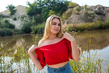 beautiful young girl in a T-shirt and short shorts posing in the summer near the lake