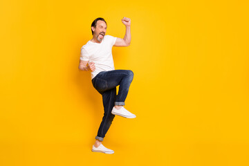 Fototapeta na wymiar Profile photo of excited crazy man raise fists open mouth wear white t-shirt jeans shoes isolated yellow background
