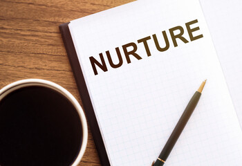 NURTURE - text on notepad on wooden desk.