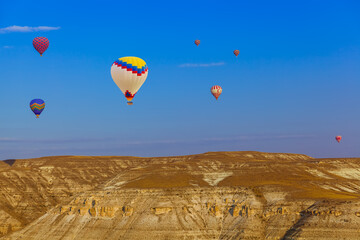 Hot air balloon flying over rocky landscape at sunrise - Cappadocia Turkey