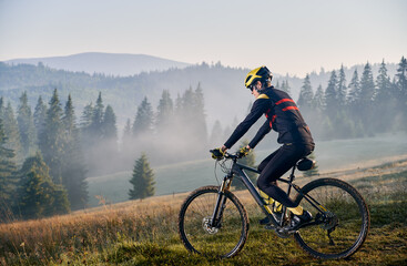 Young man riding bicycle in the mountains in early morning