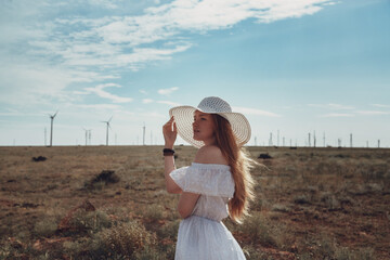 A beautiful redheaded woman in a white dress and hat on a sweltering day