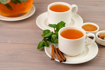 Black tea served with cinnamon sticks and mint on brown table