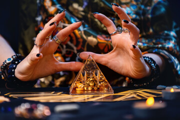 A witch is guessing over a magical glass pyramid. Hands close-up. The concept of astrology and divination