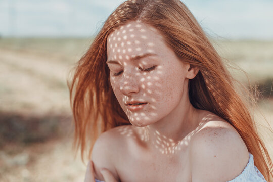 A beautiful redheaded woman in a white dress and hat on a sweltering day