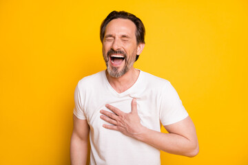 Photo of happy funky mature man laugh good mood joke hold hand chest isolated on yellow color background