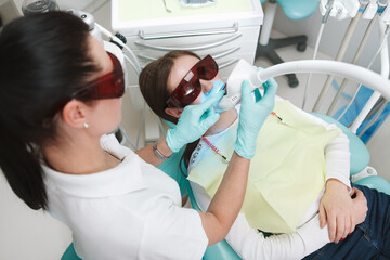 Top view shot of a female dentist doing teeth whitening for patient
