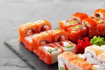 Set of various sushi rolls served on gray background