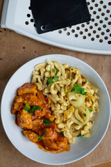 Spaetzle or Spätzle egg noodle pasta with chicken, onions and seasoning. Traditional European cuisine dish (Swabian, German, Austrian, Hungarian). Gluten free Knöpfle bowl with a grater in background.