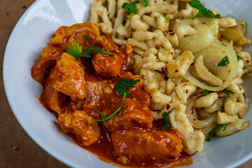 Spaetzle or Spätzle egg noodle pasta with chicken, onions and seasoning. Traditional European cuisine dish (Swabian, German, Austrian, Hungarian). Handmade gluten free Knöpfle bowl ready to eat.