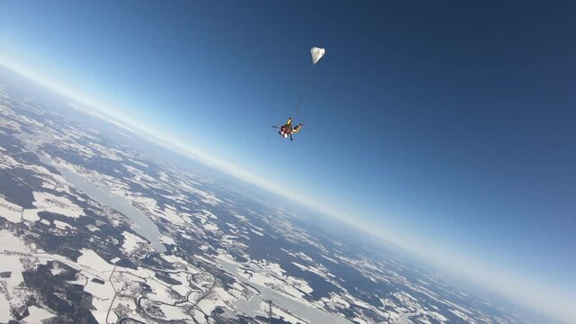 Skydiving. Tandem jump. Winter season. Man and woman are in the sky.