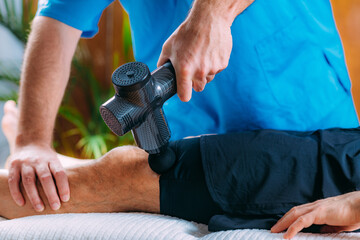 Therapist Treating Patient&rsquo;s Quadriceps Muscle with Massage Gun