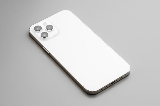 Modern white smartphone with triple-lens camera on gray background