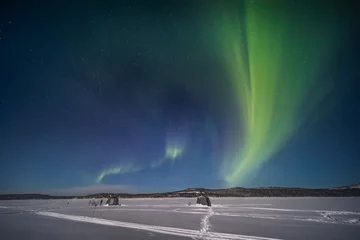 Fototapeten The northern lights over a frozen river in Swedish Lapland © PawelUchorczak