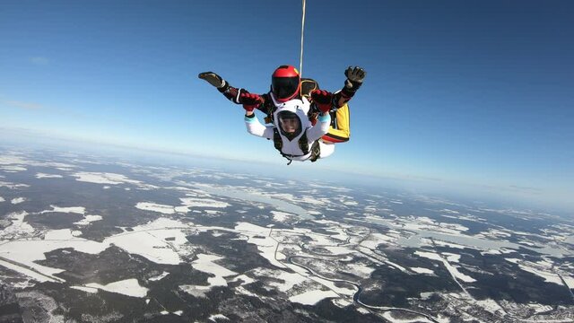 Skydiving. Tandem jump. Winter season. Man and woman are in the sky.