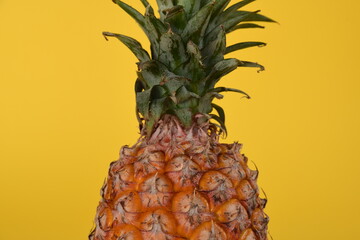 Ripe pineapple on yellow background.