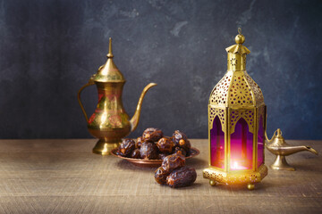 Lightened lantern and dates fruit on wooden table over dark background. Ramadan kareem holiday celebration concept