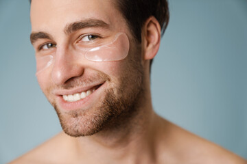 Obraz premium Shirtless white man with under eye patches smiling at camera