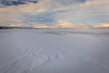 Fototapeta na wymiar The frozen lake Torneträsk in Swedish Lapland. Beautiful ice forms create an amazing sight.