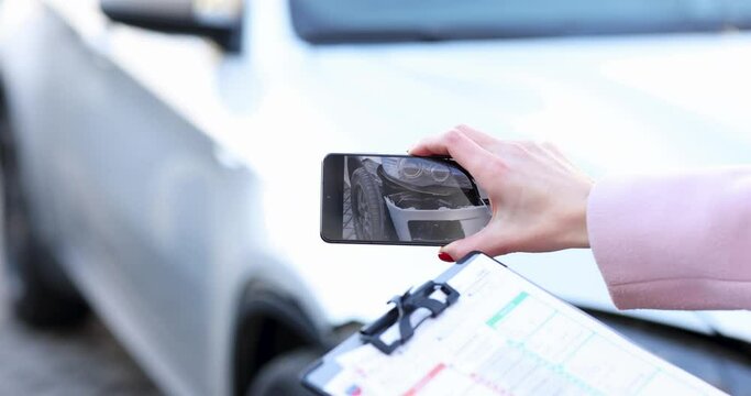 Insurance agent holding document in hands and filming wrecked car on phone camera 4k movie