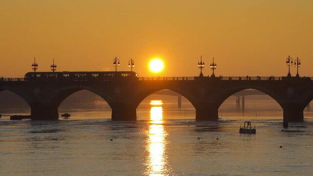 Pont de Pierre bridge at sunrise in Bordeaux, France with a tram crossing the bridge