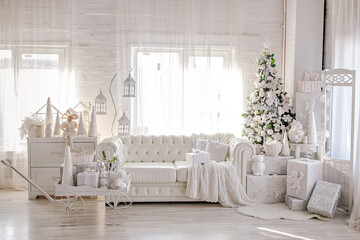 Christmas studio interior in white colors during daytime with a chester style sofa, Christmas tree with presents, chest of drawers and two widows at the background