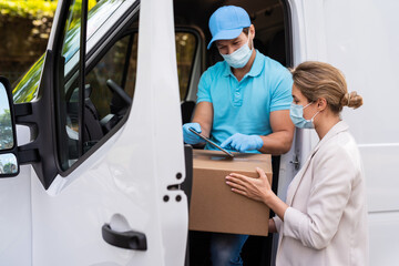 Woman receiving package from the delivery man on a van