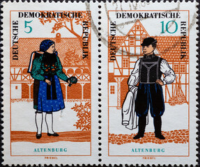 GERMANY, DDR - CIRCA 1966  : a postage stamp from Germany, GDR showing a woman and a man in the folk costume of Altenburger. In front of a half-timbered house
