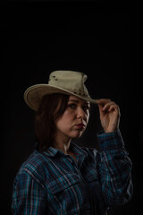 Portrait of a young beautiful girl in a cowboy hat on a black background, soft focus