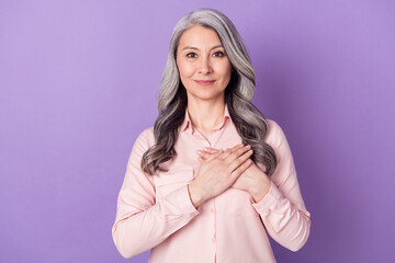 Portrait of attractive cheery honest affectionate woman touching heart praying isolated over violet purple color background - obrazy, fototapety, plakaty