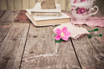 Pink Flowers and old books and tea cups on rustic wooden table. Vintage Floral background.