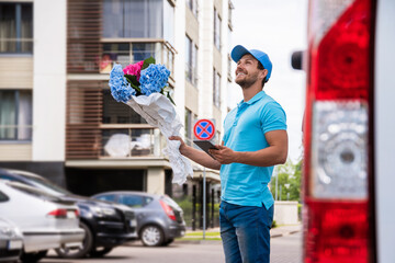 Happy courier with a tablet PC during flowers delivery