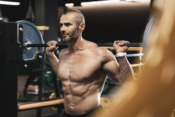 Bodybuilder during his workout with a barbell in the gym