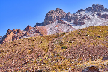 Ancient moraine overgrown with lichens and juniper bushes on a background of spectacular bizarre...