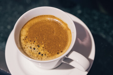 top view of morning hot black coffee cup with brown creama on dark table