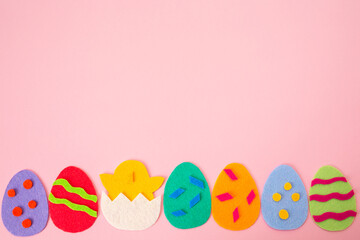 Fototapeta na wymiar Happy Easter holiday concept. Cut out the felt applications of colorful eggs and the chicken hatched from the egg. Pink background. Flat lay. Copy space