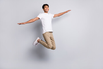 Photo of crazy carefree guy jump look empty space plane pose wear white t-shirt trousers sneakers...