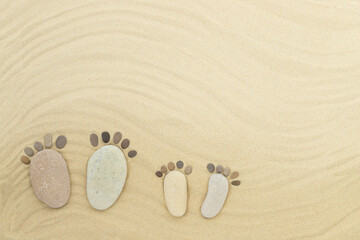 Summer sandy backdrop with sea pebbles in the form of feet 