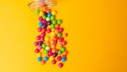 colorful candies poured from a glass jar on a colored background