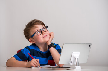 Child boy in glasses think and dream. Kid of primary school reading book. Online remote computer education. Child having computer video conference chat during quarantine and coronavirus outbreak.