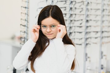 Cute little girl with new glasses in shop
