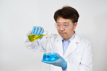Portrait of a middle-year Asian male scientist wearing a white lab gown and gloves and holding an experimental container in his hand.
