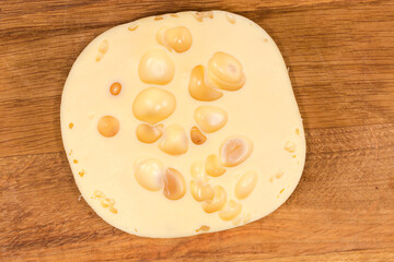 Top view of Swiss-type cheese on wooden cutting board