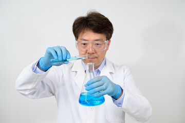 Portrait of a middle-year Asian male scientist wearing a white lab gown and gloves and holding an experimental container in his hand.
