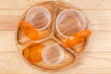 Open plastic food storage containers on wooden dish, top view