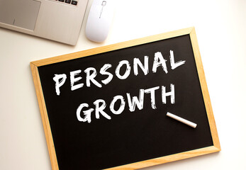 Text PERSONAL GROWTH written in chalk on a slate board. Office desk.