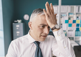 Stressed businessman doing a facepalm gesture
