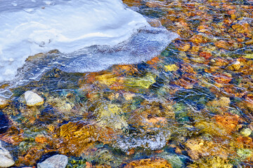 Concept of beauty and grandeur of nature: crystal clear water in a mountain river with a spectacular ice edge