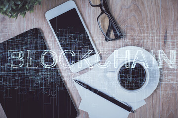 Double exposure of blockchain theme hologram over table with phone. Top view. Crypto technology...
